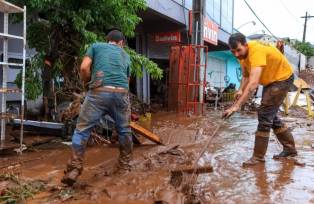 Moradores tentam limpar a sujeira e retirar a lama em região afetada pelas enchentes no Rio Grande do Sul (Foto: Gustavo Mansur/Palácio Piratini)